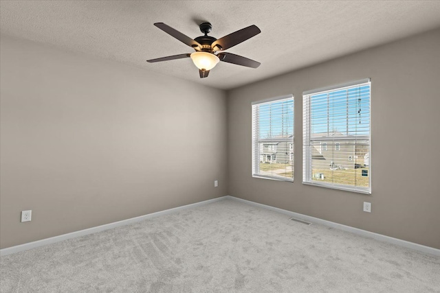 spare room featuring carpet flooring, visible vents, baseboards, and a textured ceiling