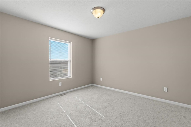 spare room with baseboards, visible vents, and carpet floors