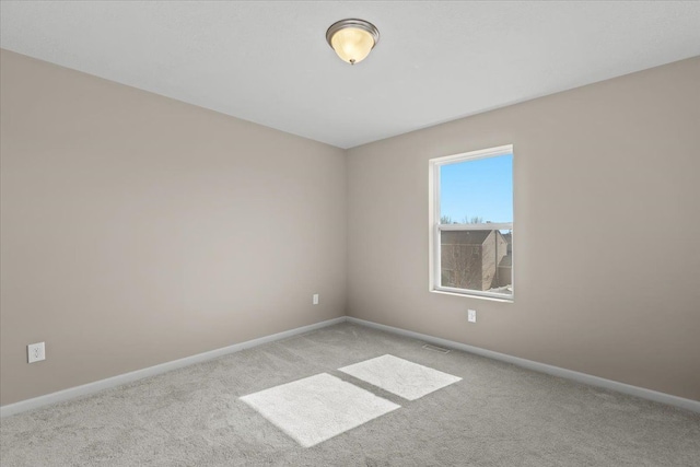 empty room with carpet, visible vents, and baseboards