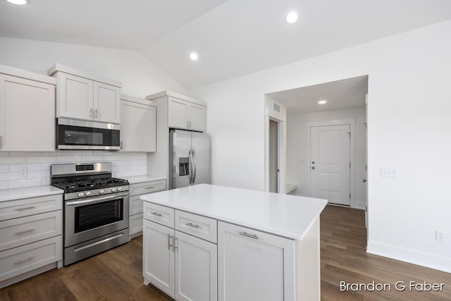 kitchen with lofted ceiling, stainless steel appliances, light countertops, dark wood-type flooring, and backsplash