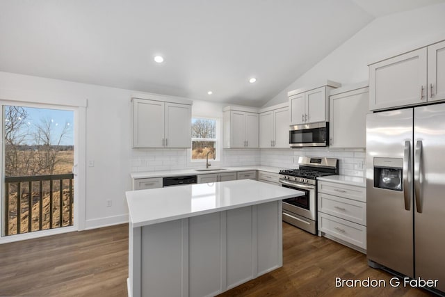 kitchen featuring tasteful backsplash, appliances with stainless steel finishes, lofted ceiling, and a sink