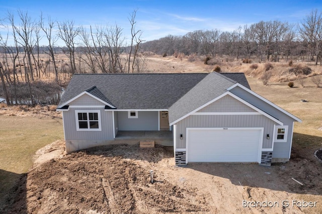 view of front of home featuring a garage, driveway, and a shingled roof