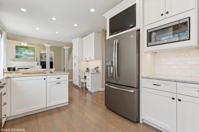 kitchen with light wood finished floors, tasteful backsplash, built in microwave, stainless steel refrigerator with ice dispenser, and ornate columns