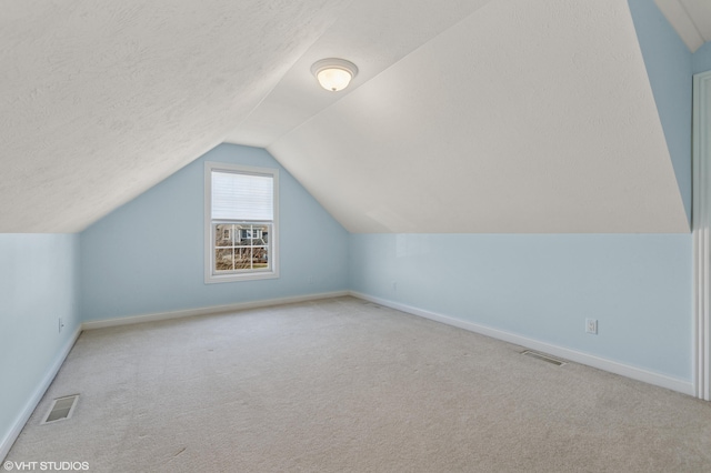 bonus room featuring visible vents, a textured ceiling, carpet flooring, and vaulted ceiling