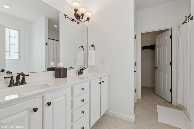 bathroom featuring tile patterned flooring, double vanity, a notable chandelier, and a sink