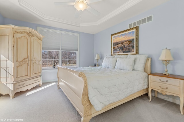 carpeted bedroom featuring visible vents, a ceiling fan, crown molding, and a tray ceiling