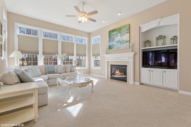 carpeted living area with built in features, baseboards, a ceiling fan, and a tile fireplace