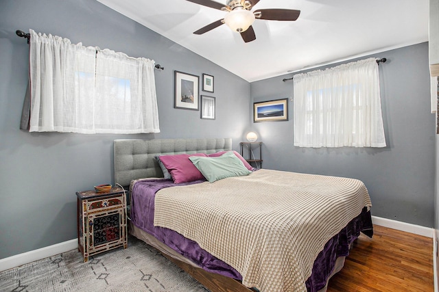 bedroom featuring baseboards, lofted ceiling, wood finished floors, and a ceiling fan