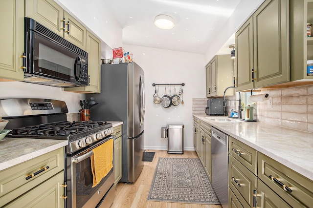 kitchen with green cabinetry, stainless steel appliances, and a sink