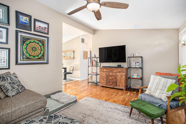 living area with visible vents, baseboards, lofted ceiling, wood finished floors, and a ceiling fan