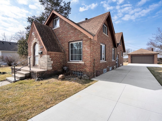 view of property exterior with brick siding, a yard, a shingled roof, and an outdoor structure