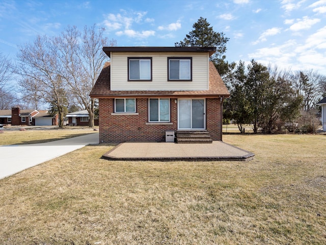 view of front of property featuring a front yard, driveway, a shingled roof, entry steps, and brick siding