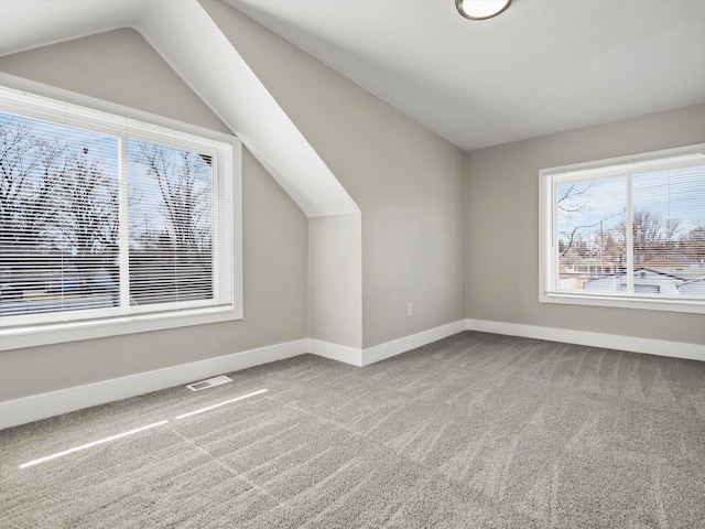 additional living space featuring visible vents, lofted ceiling, carpet, and baseboards