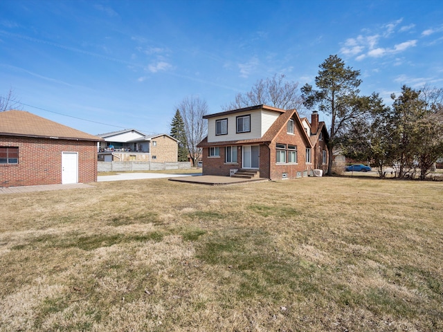 view of front of house featuring a front lawn, entry steps, fence, brick siding, and a chimney