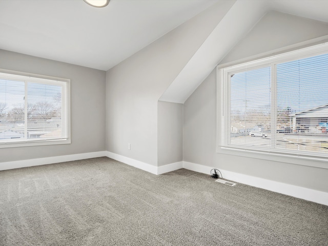 bonus room featuring baseboards, carpet floors, visible vents, and vaulted ceiling