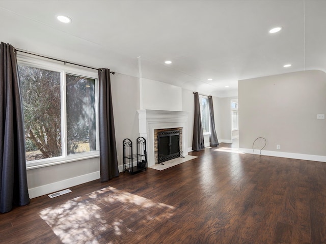 unfurnished living room featuring a fireplace with flush hearth, wood finished floors, recessed lighting, and baseboards