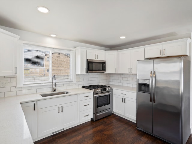 kitchen with a sink, dark wood-style floors, stainless steel appliances, light countertops, and decorative backsplash