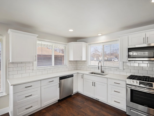 kitchen with a sink, backsplash, appliances with stainless steel finishes, and dark wood-style floors