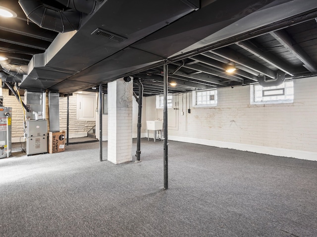 below grade area with visible vents, heating unit, water heater, brick wall, and stairs