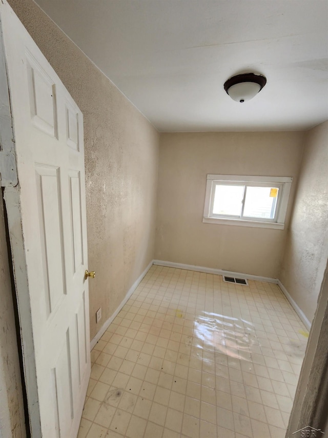 empty room with visible vents, baseboards, and a textured wall