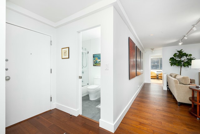 hallway with track lighting, baseboards, and wood finished floors