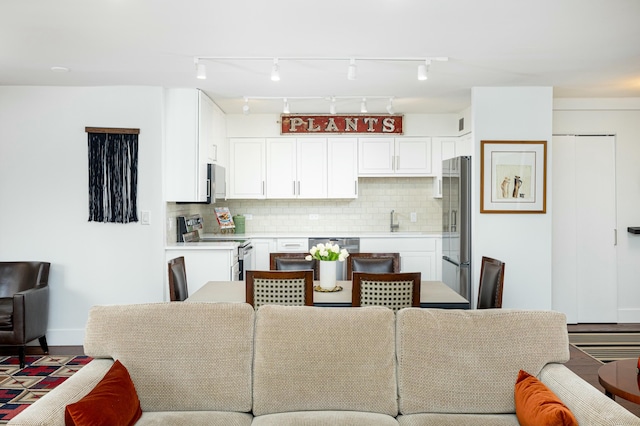 interior space featuring white cabinetry, backsplash, and appliances with stainless steel finishes