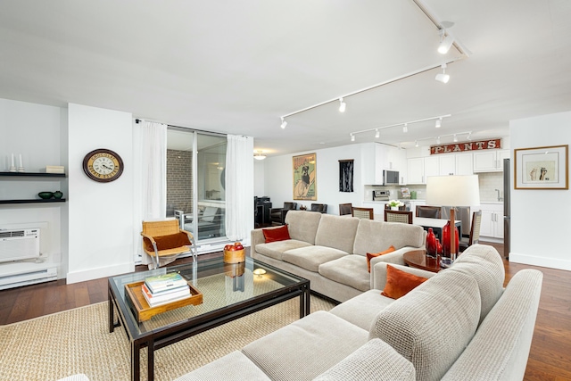 living room with baseboards, dark wood-style flooring, and a wall mounted AC