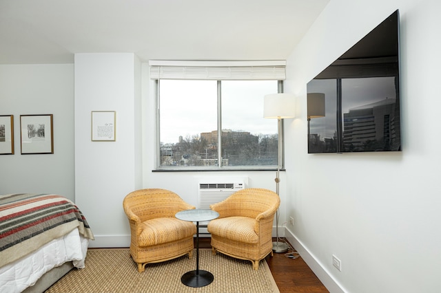 bedroom featuring a wall mounted air conditioner, baseboards, and wood finished floors