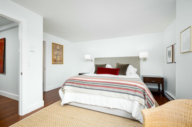 bedroom featuring wood finished floors, baseboards, and a baseboard radiator