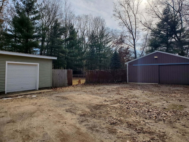 view of yard featuring an outdoor structure, fence, a garage, and a pole building