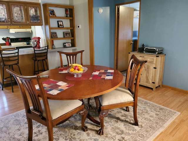 dining space featuring light wood-style flooring and baseboards