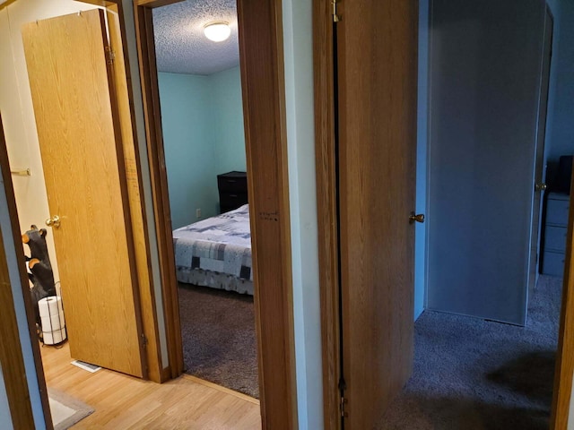 hallway featuring wood finished floors, visible vents, and a textured ceiling