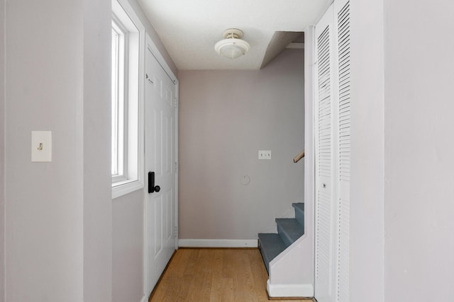 hall with stairway, light wood-type flooring, and baseboards