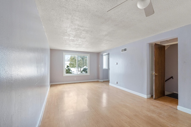 unfurnished room with visible vents, baseboards, ceiling fan, light wood-style flooring, and a textured ceiling