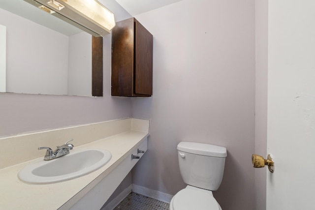 half bath with vanity, toilet, baseboards, and tile patterned flooring