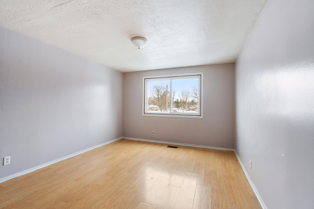 unfurnished room with visible vents, baseboards, light wood-style floors, and a textured ceiling