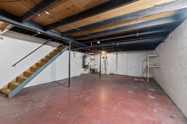 unfinished basement featuring concrete block wall, stairs, and a sink