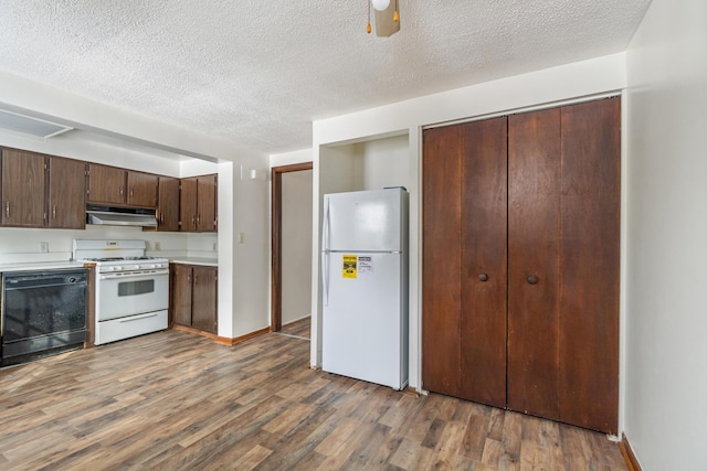 kitchen featuring white appliances, wood finished floors, dark brown cabinetry, light countertops, and under cabinet range hood