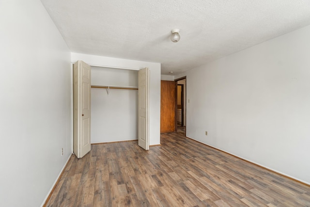 unfurnished bedroom with a closet, baseboards, a textured ceiling, and wood finished floors