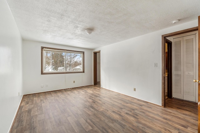 empty room featuring a textured ceiling and wood finished floors