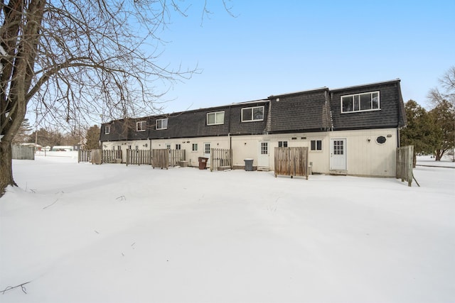 snow covered rear of property featuring fence