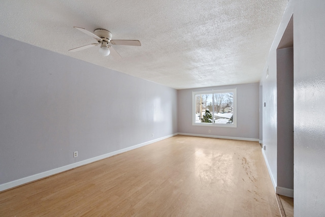 spare room with light wood-type flooring, baseboards, a textured ceiling, and a ceiling fan