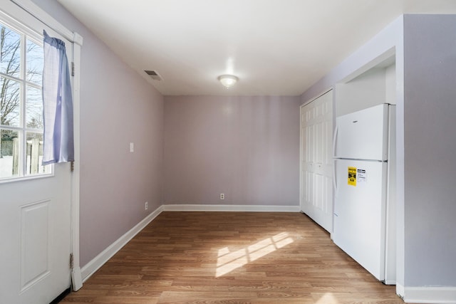 interior space with light wood-style flooring, plenty of natural light, visible vents, and freestanding refrigerator