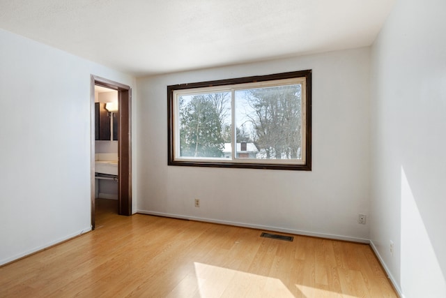 spare room with visible vents, baseboards, and wood finished floors