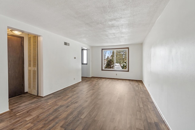 spare room featuring visible vents, a textured ceiling, and wood finished floors