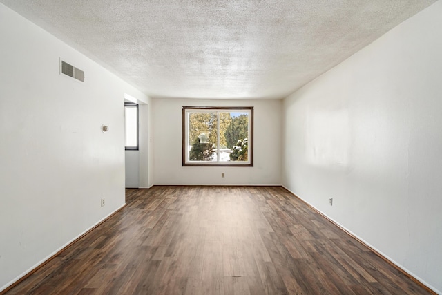 unfurnished room featuring dark wood-style floors, visible vents, and a textured ceiling