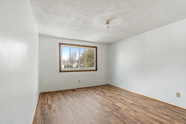 spare room featuring a textured ceiling and wood finished floors