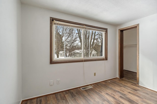 unfurnished bedroom with visible vents, wood finished floors, a closet, and a textured ceiling