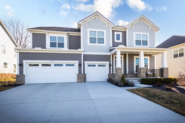 craftsman inspired home with a porch, concrete driveway, a garage, and stone siding