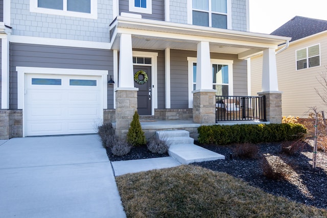 doorway to property featuring a garage, stone siding, covered porch, and concrete driveway